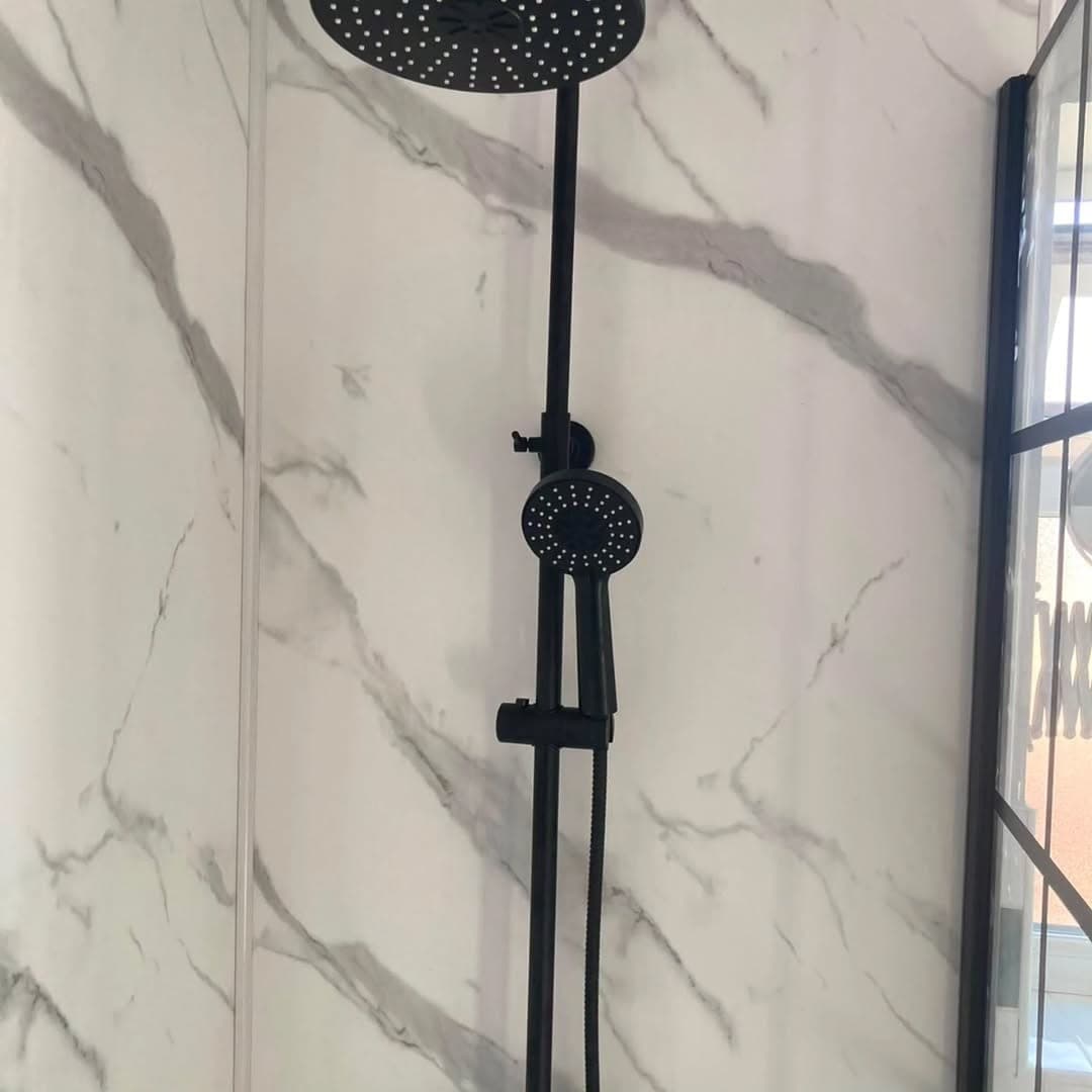Marble-effect shower wall panelling with a matt black rainfall shower head and handset