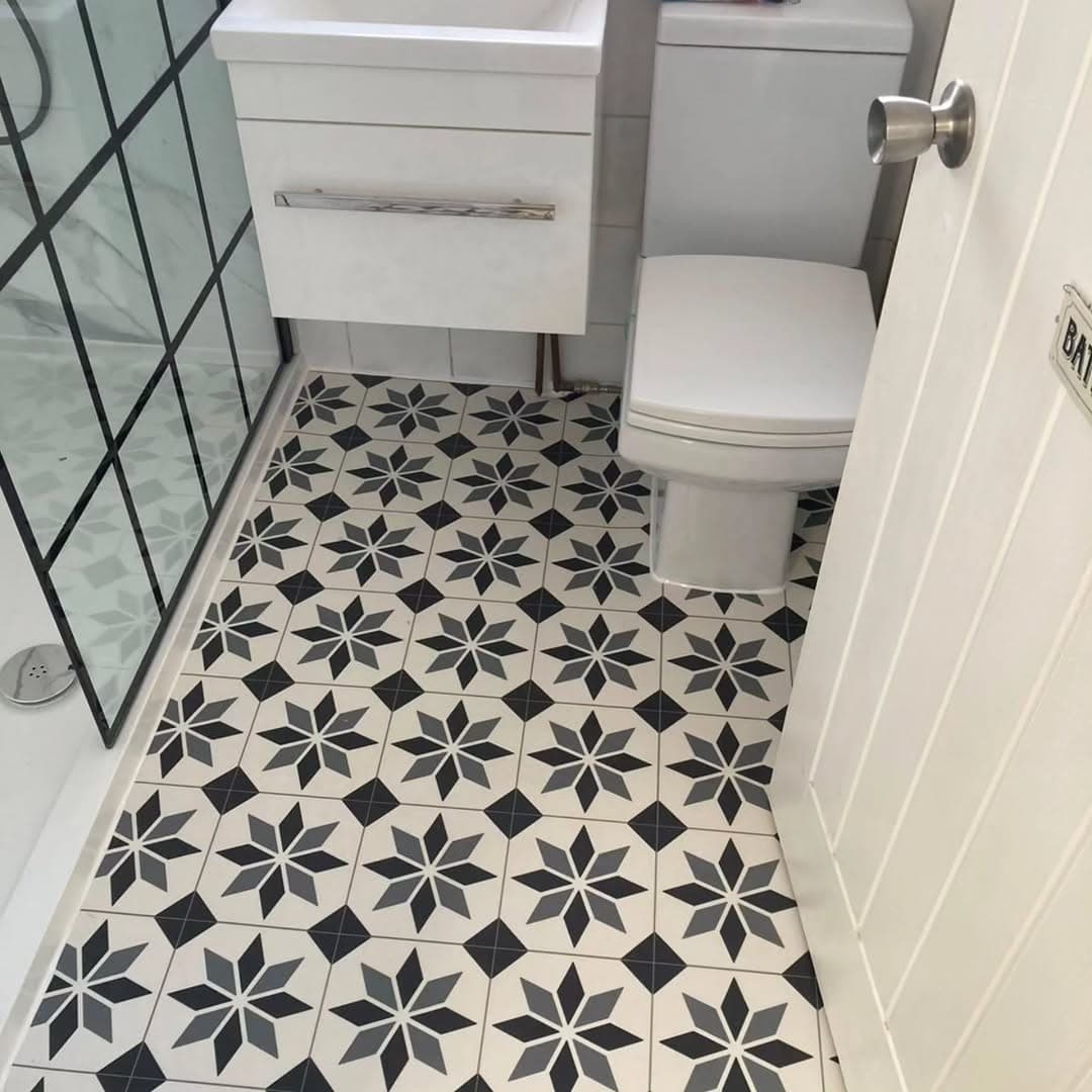 Bathroom floor in black and white patterned tiles, cut neatly around a close-coupled toilet and vanity unit