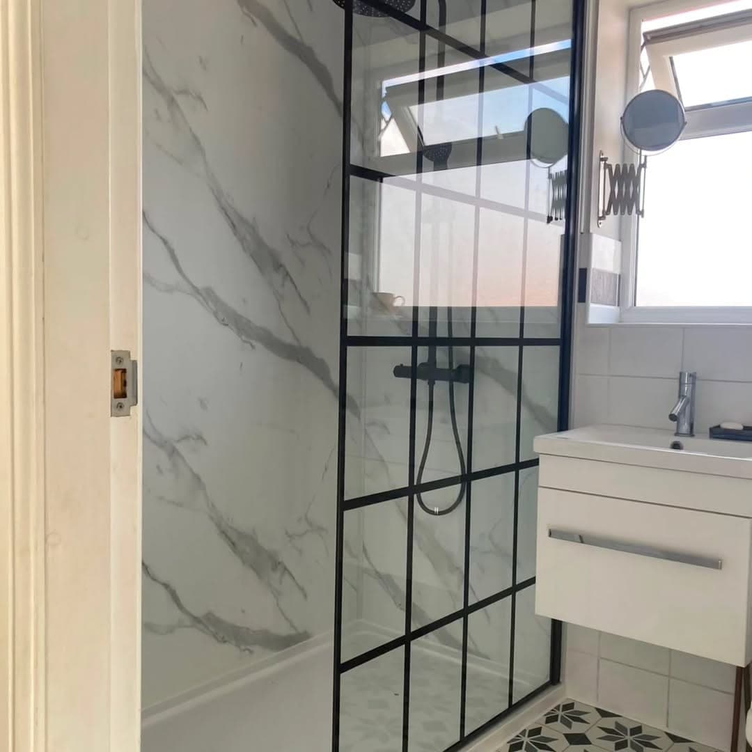 Bathroom with a wall-hung white vanity unit and basin beside a window, with the crittall-style shower screen alongside