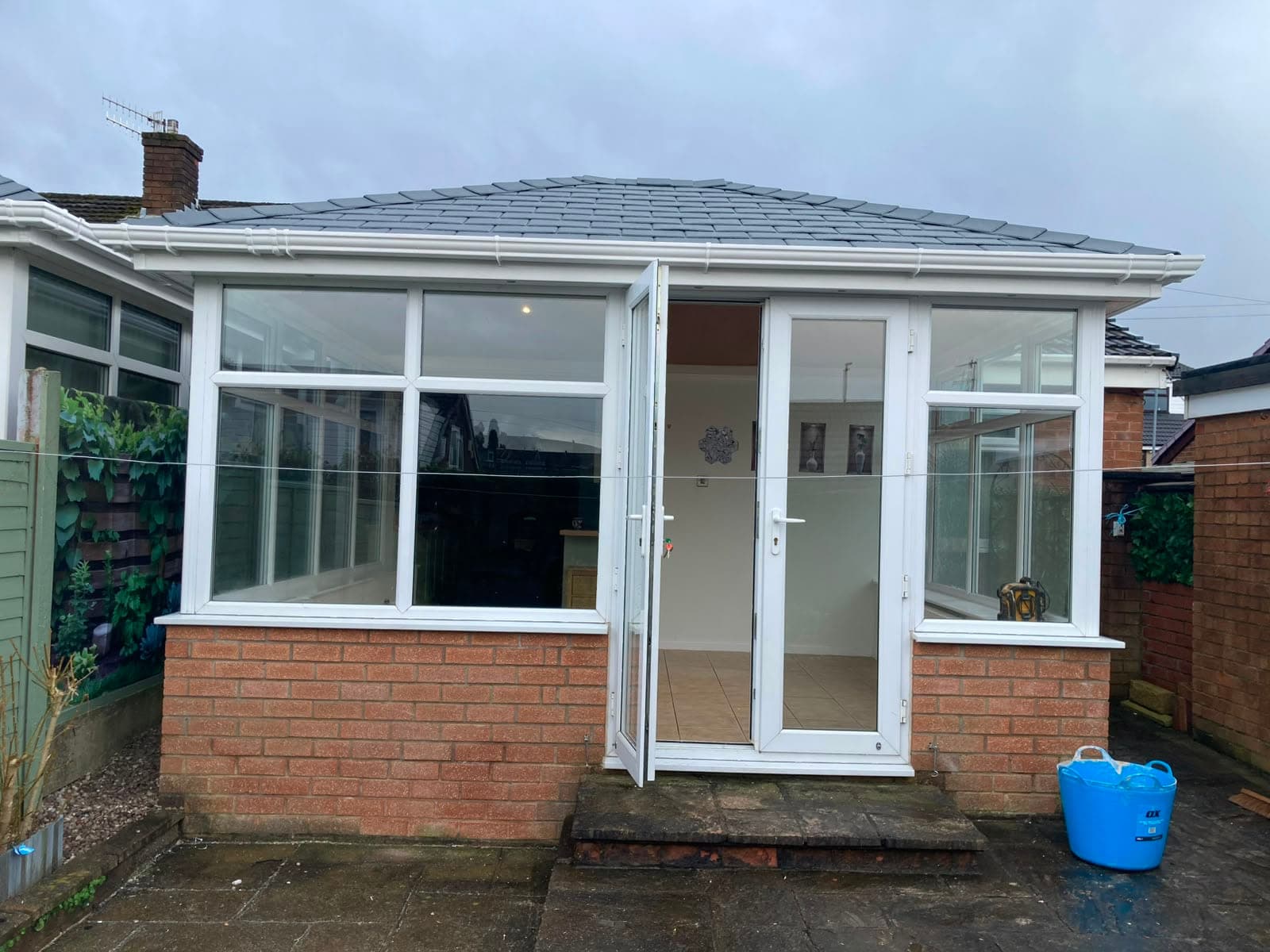 White conservatory with French doors and a newly fitted grey tiled warm roof above