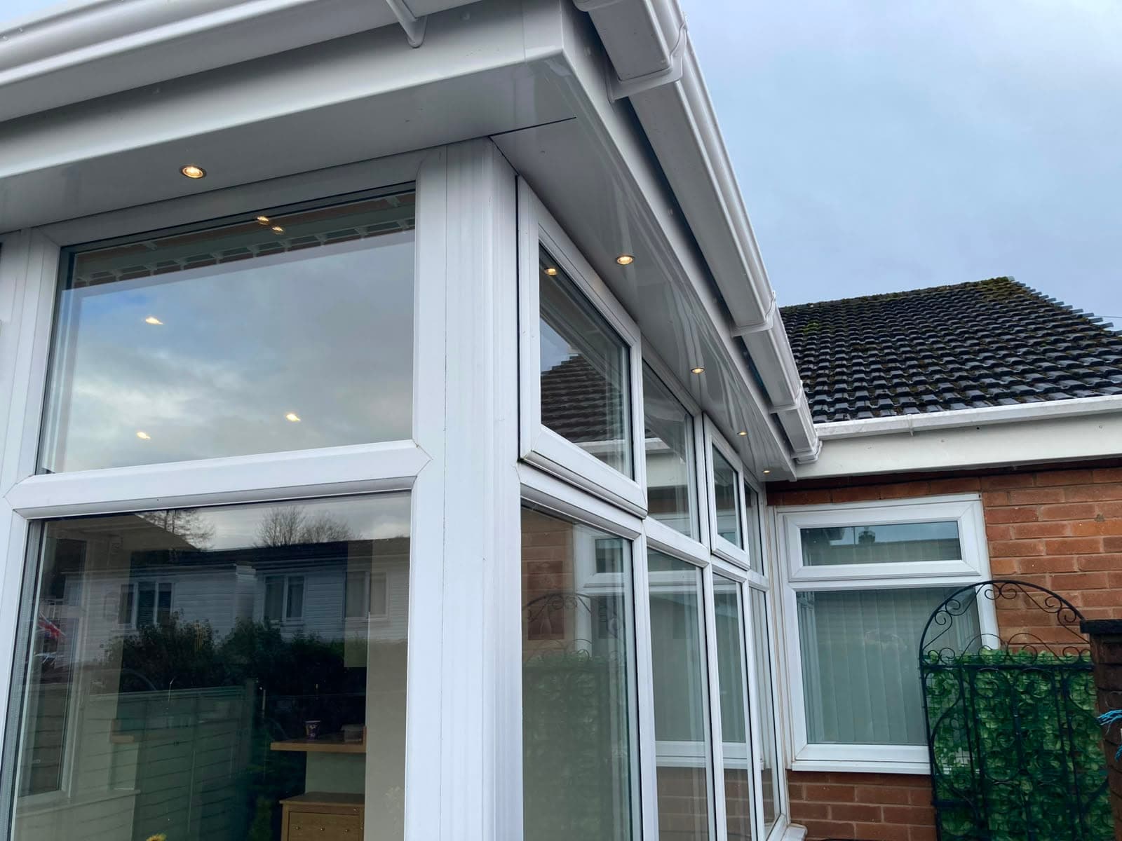 Converted conservatory seen from inside and outside, with white frames and a new insulated roof